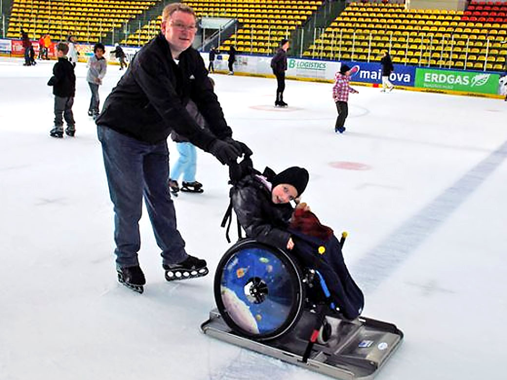 Eisläufer mit Kind im Rollstuhl auf dem Eis